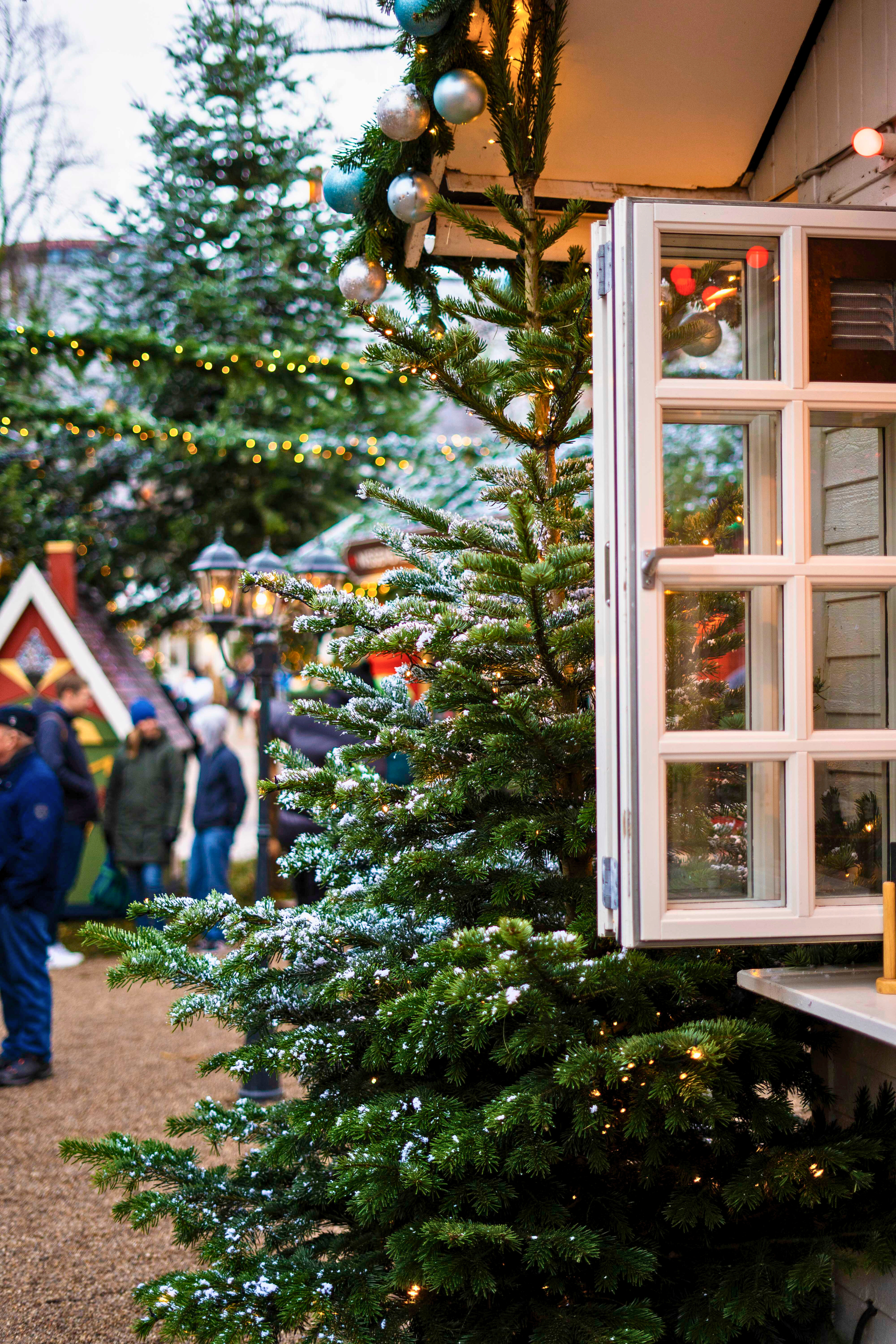 Dekoreret juletræ ved en bod i Tivoli med lys og pynt.