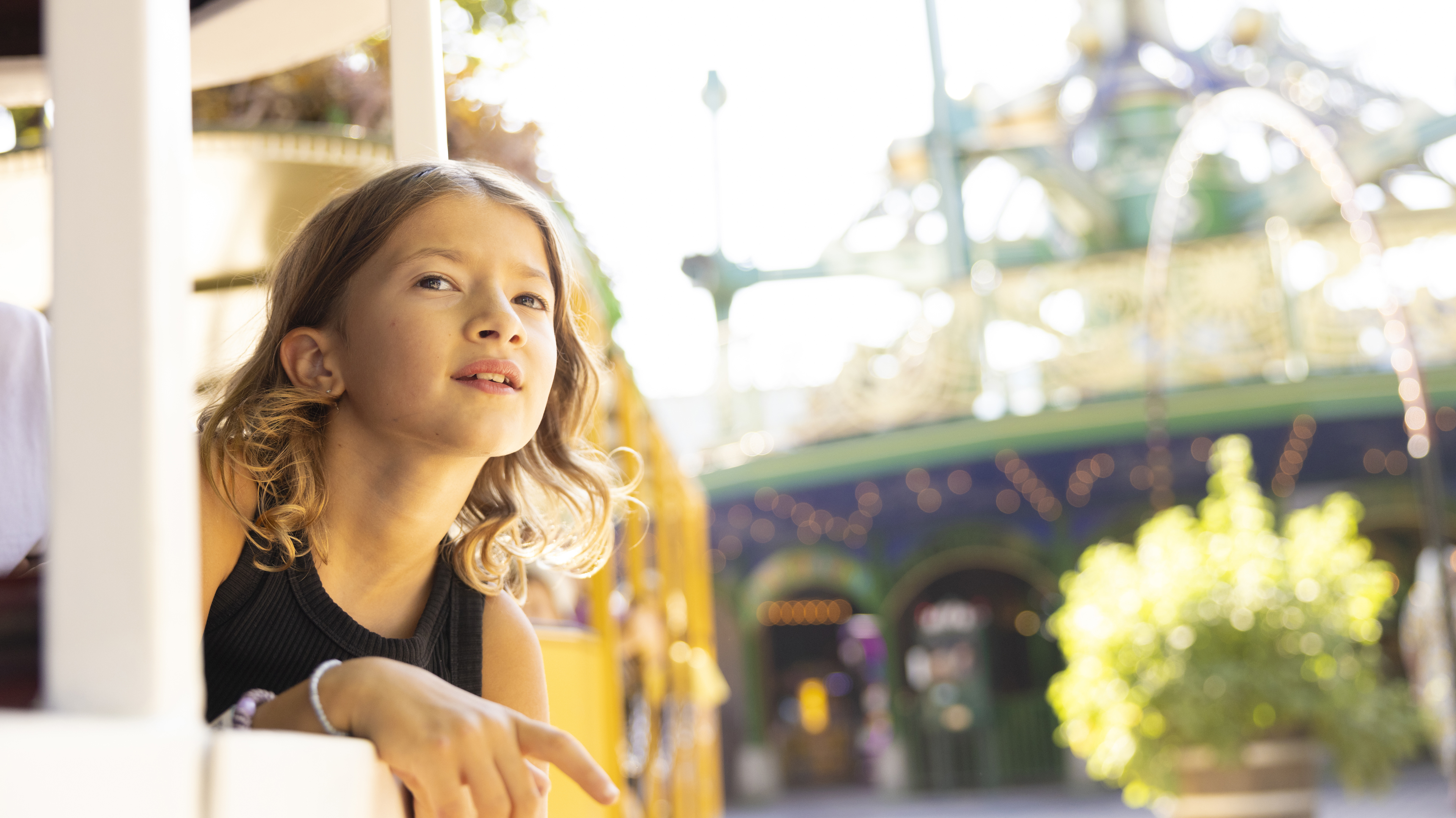 A girl sitting on Line 8 Tram in Tivoli, gazing out as she rides through the park.